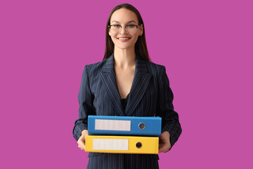 Young businesswoman with document folders on purple background