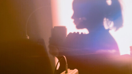 Shadow of girl drinking coffee from mug on sunny day. Silhouette of female person in the morning. Woman with thermos cup at home. Film grain texture. Soft focus. Blur