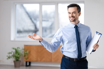 Portrait of male real estate agent with clipboard showing new apartment