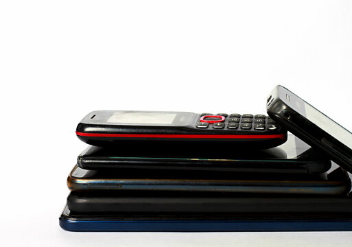 old mobile phones piled up on a table with white background no people stock image stock photo