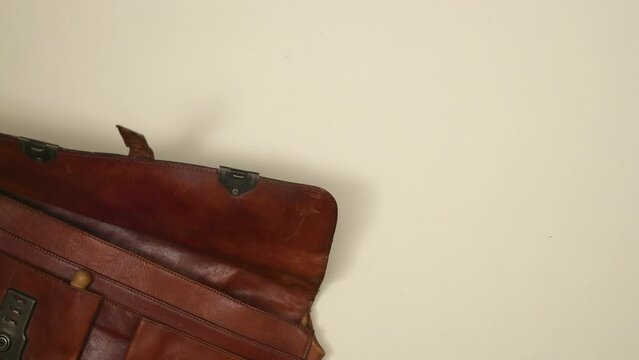 Workers daily equipment in a brown leather vintage suitcase. Top view, 4K stop motion animation. 