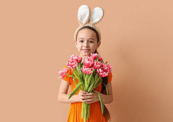 Cute little girl with bunny ears and tulip flowers on beige background. Easter celebration