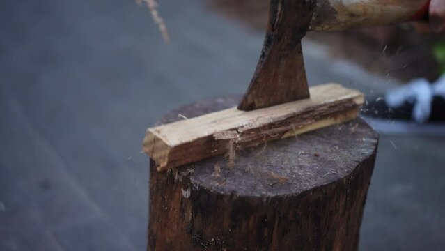 Close-up. A man is trying to cut a piece of wood lying on a log with an axe while standing outdoors. Chopping wood for a fire. Chopping a wood with an ax that lying on a log. Preparation of firewood