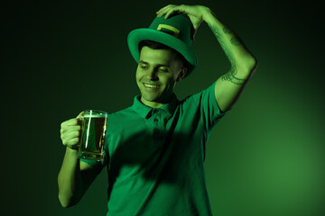 Happy young tattooed man with beer on dark green background. St. Patrick's Day