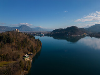 Aerial view of Lake Bled with the castle. Calm deep blue water surface with reflection. Panoramic view on a mountainous landscape in Slovenia.