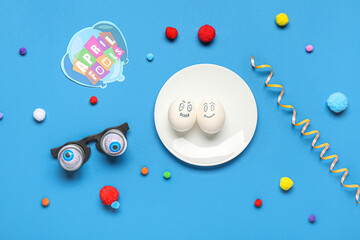 Plate with eggs, funny glasses and decor on blue background. April Fool Day