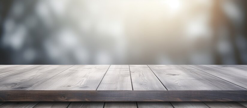 A wooden table stands in focus against a blurred gray background. The tables intricate grain and texture are highlighted in the foreground, while the background remains indistinct.