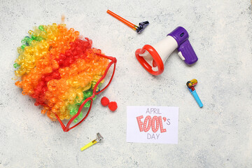 April Fool's Day card with megaphone, clown wig and funny glasses on light grunge background. April...