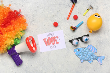April Fool's Day card with megaphone, clown wig and funny glasses on light grunge background. April...