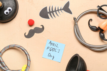 Plumber's items with funny glasses, decor and sticky note on beige background. April Fools Day