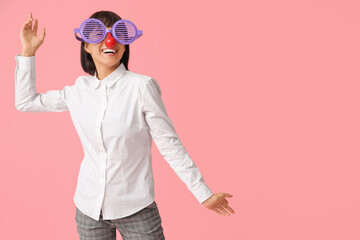 Young laughing businesswoman with clown nose on pink background. Fool's day