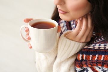 Young woman with cup of hot tea on white background