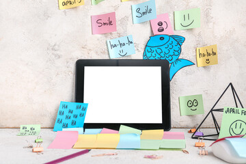 Tablet and sticky notes on grunge background. April Fools Day prank