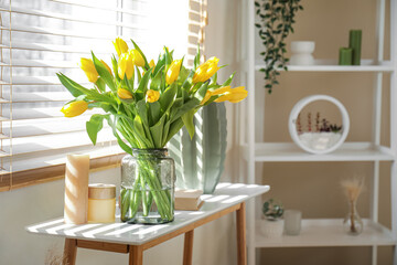Vase of tulips with candles near window in living room