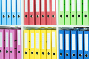 Multi-colored file folders on business office shelves, document archive, accounting or reports concept background