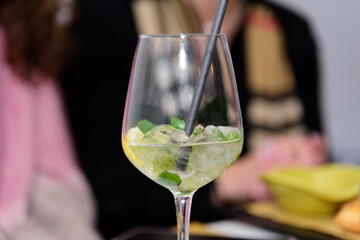A glass of Hugo cocktail on the table at a fun party of friends in a restaurant, evening aperitif