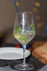 A glass of Hugo cocktail on the table at a fun party of friends in a restaurant, evening aperitif