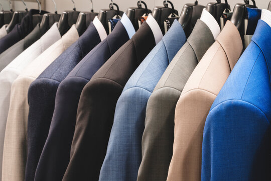 Row of men's suits hanging. Elegant jacket hanged on a clothes rack.