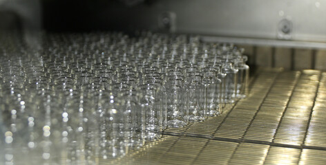 a big lot vaccine empty injection glass vials moving into liquid filling chamber with liquid medicine in an injection production line in a pharmaceutical manufacturing company