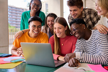 A large group of young multiracial students gathered in classroom smiling and having fun watching...