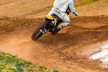 Person racing a motorcycle on a dirt track with helmet and protective gear