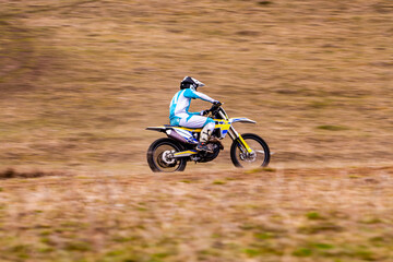 A person rides a dirt bike downhill with a motocross helmet