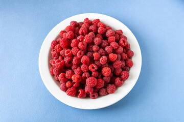 A white plate full of raspberries