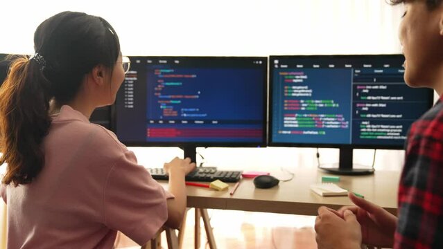 Slow motion back end software developer engineer for computer programming working together on debugging writing computing code, solving complex algorithms display on monitor in office. Burgeoning