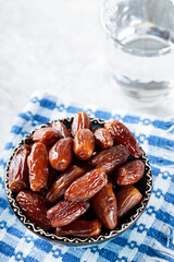 Medjool Dates Bowl and Glass of Water on Concrete Background, Healthy Ramadan Suhour Snack, Close-up