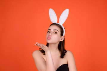 Cheerful young woman wearing Easter bunny ears holding decorative colored eggs on studio background...