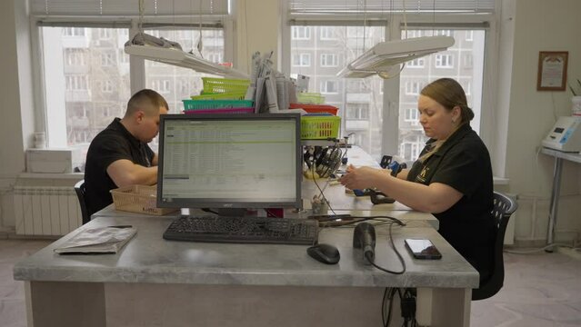 Dental laboratory specialists using the small tools. Dental laboratory specialists creating the artificial teeth substitutions. Dental laboratory specialists producing replacement teeth.