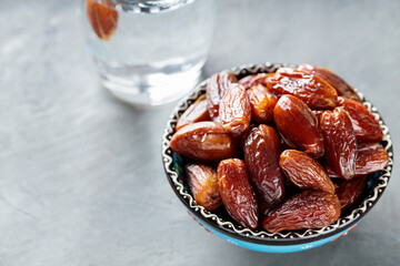 Dried Dates and Water Glass on Gray Concrete, Ramadan Suhoor Concept, Copy Space