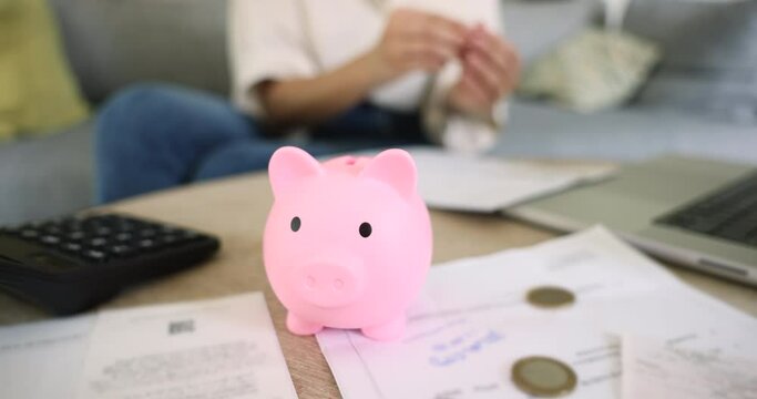 Cropped close up view unknown frugal woman drop cash, put coin into piggy bank, save money for future, thinking about tomorrow, making investment. Budget control, financial literacy, banking, economy