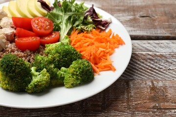 Balanced diet and healthy foods. Plate with different delicious products on wooden table, closeup