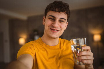 man young caucasian male hold glass of water at home