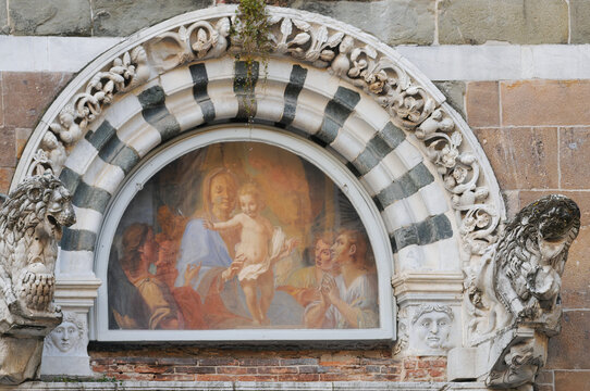 Ornate sculptured marble arch with fresco of Virgin Mary and baby Jesus on the portal of the San Giustochurch in Lucca, Tuscany, Italy
