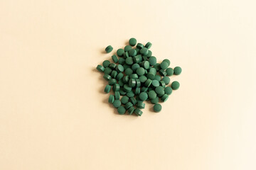 Flat Lay Vitamin, Easy To Swallow Green Pills Of Natural Spirulina On Beige Background. They Are Made Of Blue-green Algae With Strong Antioxidant Effects. Horizontal.