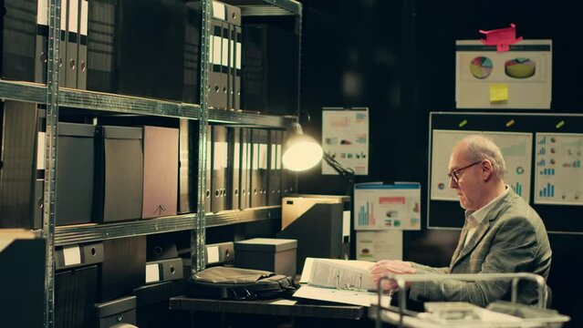 Private investigator organizes archived files for easy access, searching for old file cases to cross reference data. Law enforcement agent looking for classified folders in archive room. Camera A.