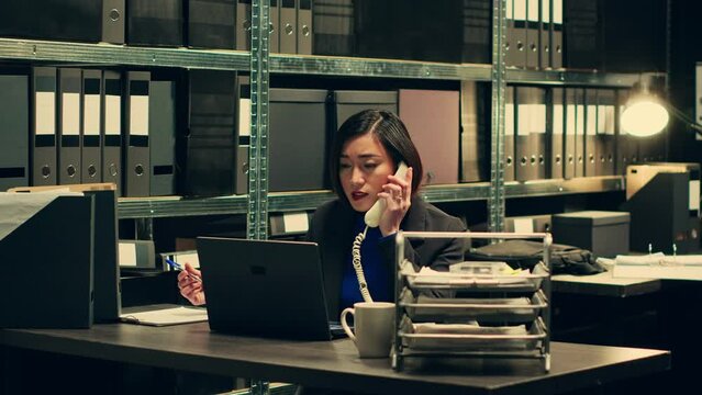 Private detective conducting background check on landline phone call, asking forensic experts about suspects associated with archived cases. Agent searches for relevant information. Camera A.