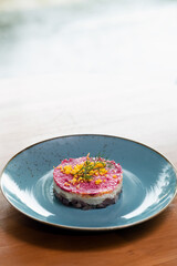 Layered 'Shuba' salad arranged in a circular shape on a blue plate.