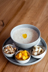 Oatmeal porridge with butter in a bowl, served with fruits and nuts.