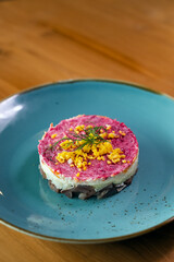 Layered 'Shuba' salad arranged in a circular shape on a blue plate.