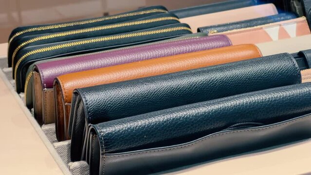 A close-up of women's leather wallets on display in a store window