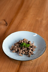 Finely chopped pieces of boiled meat on a plate decorated with a sprig of herbs.