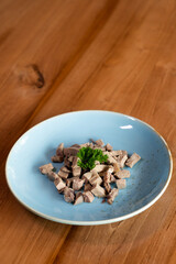 Finely chopped pieces of boiled meat on a plate decorated with a sprig of herbs.