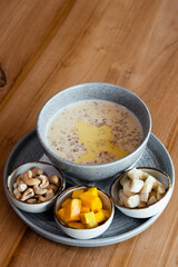 Oatmeal porridge with butter in a bowl, served with fruits and nuts.