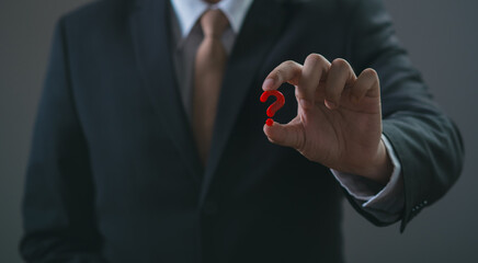 Man hand on dark background holding and using digital red question marks Sign holographic. The...