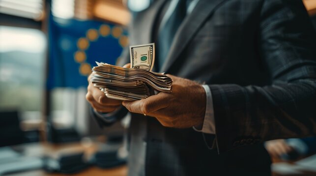 Businessman in suit with hands holding euro bills against blurred eu flag, copy space available
