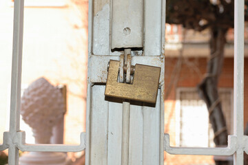 A metal square lock hangs on a metal old grill on the window - apartment security