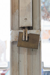 A metal square lock hangs on a metal old grill on the window - apartment security